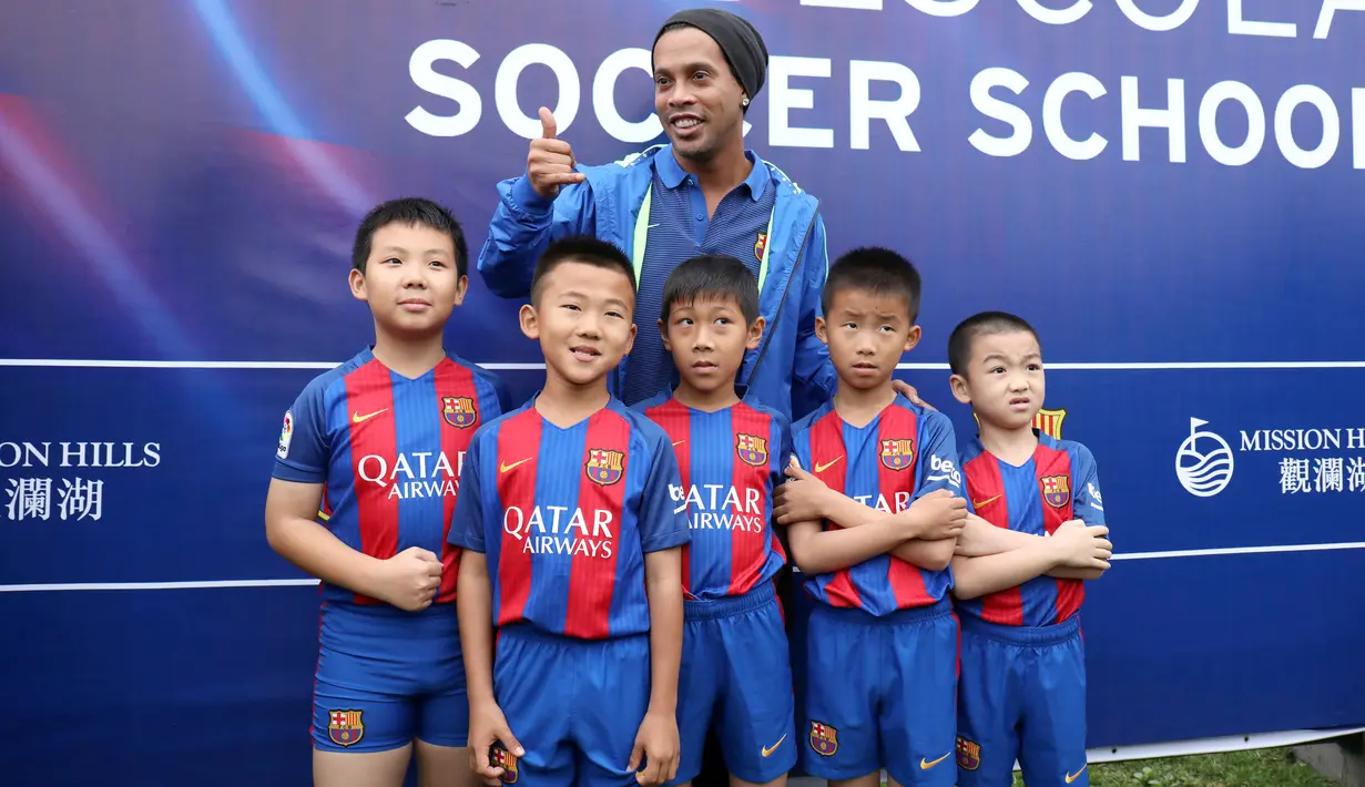 Ronaldinho berfoto bersama dengan sejumlah pemain sepak bola cilik saat peluncuran akademi sepak bola di China (24/2). Dalam peresmian akademi sepak bola tersebut Ronaldinho ditunjuk sebagai salah satu duta dari Barcelona. (Handout / Mission Hills / AFP)