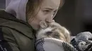 Seorang wanita yang dievakuasi dari Irpin menangis mencium kucing yang dibungkus selimut di titik triase di Kyiv, Ukraina, 11 Maret 2022. Dalam eksodus lebih dari 2,5 juta orang yang melarikan diri dari invasi Rusia, terdapat hewan peliharaan yang tidak dapat ditinggalkan. (AP Photo/Vadim Ghirda)
