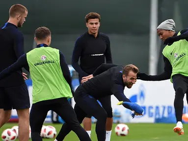 Penyerang Inggris Harry Kane (tengah) memegang mainan ayam di sebelah bek Inggris Ashley Young (kanan) saat mengikuti sesi latihan di Repino (10/7). Inggris akan bertanding melawan Kroasia pada babak semifinal Piala Dunia 2018. (AFP Photo/Ellis)