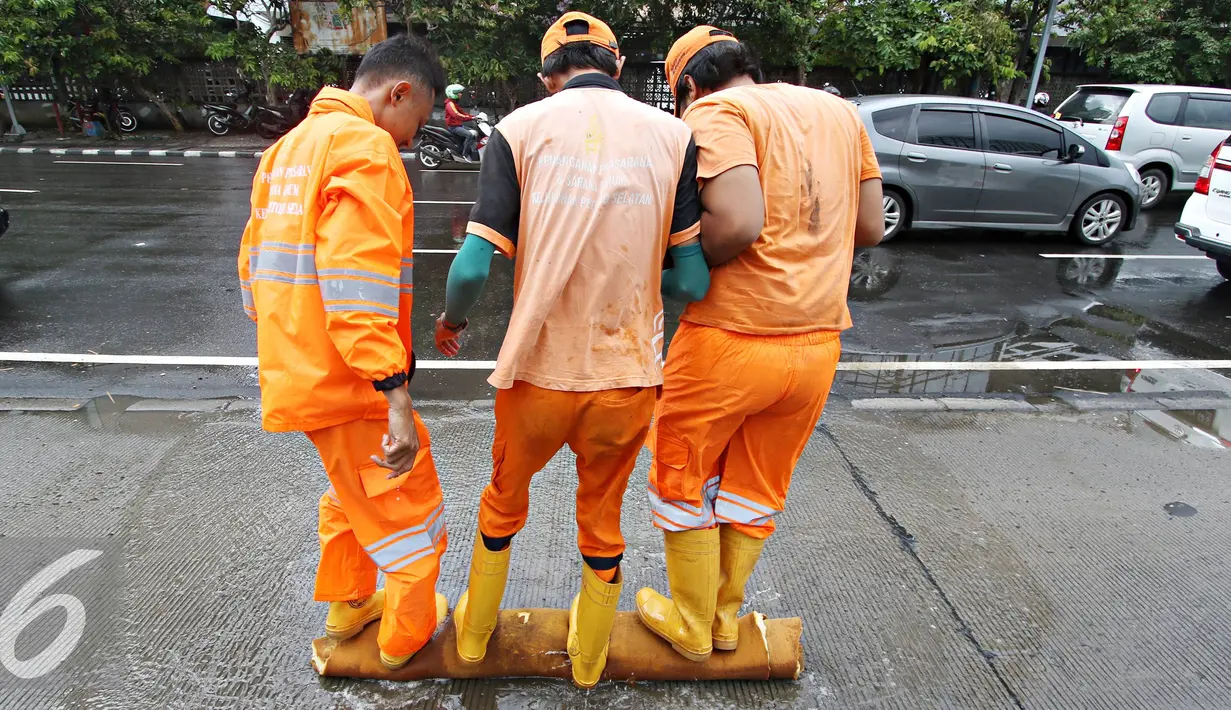 Petugas Dinas Kebersihan mengeluarkan air dari busa di Harmoni, Jakarta, Selasa (9/2). Buruknya sistem drainase membuat petugas terpaksa harus membersihkan genangan setiap kali hujan, meski dengan peralatan seadanya. (Liputan6.com/Immanuel Antonius)