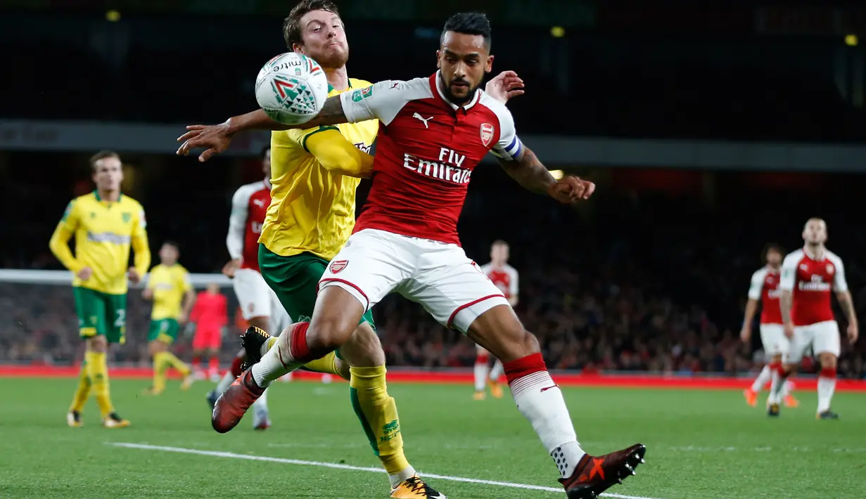 Pemain Arsenal, Theo Walcott berebut bola dengan pemain Norwich City, Angelina pada lanjutan Piala Liga Inggris di Emirates Stadium, Rabu (25/10). Edward Nketiah memborong gol Arsenal saat mengalahkan Norwich City 2-1. (AP/Alastair Grant)