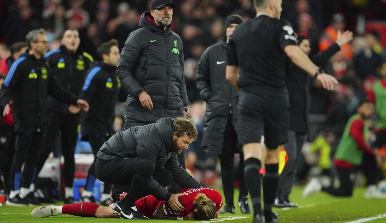 Pemain Liverpool, Kostas Tsimikas, terkapar setelah berduel dengan pemain Arsenal, Bukayo Saka pada laga pekan ke-18 Premier League 2023/2024 di Stadion Anfield, Minggu (24/12/2023). (AP Photo/Jon Super)