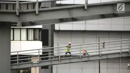 Pekerja menyelesaikan revitalisasi Jembatan Penyeberangan Orang (JPO) Gelora Bung Karno (GBK), Jakarta, Selasa (27/11). Pembangunan tiga JPO Polda Metro Jaya, GBK dan Bundaran Senayan akan dilengkapi lift, solar cell. (Liputan6.com/Faizal Fanani)