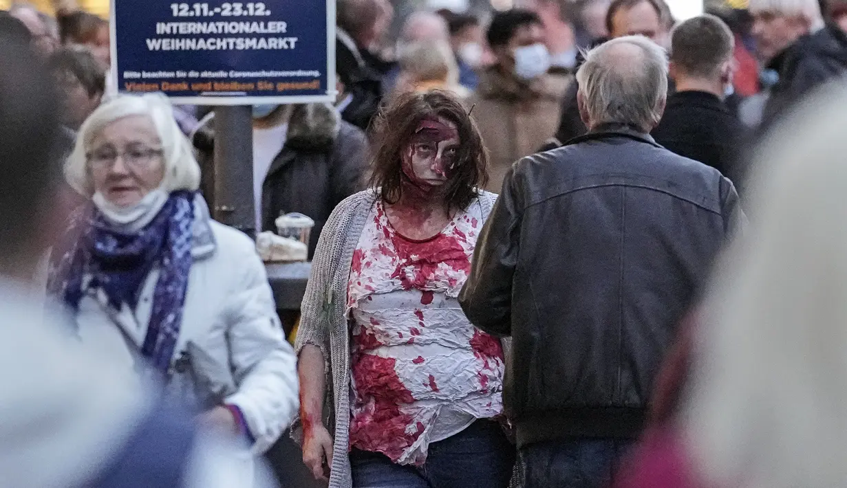 Orang-orang yang mengenakan kostum menakutkan berpartisipasi dalam Zombie Walk dan Parade Halloween tahunan di Essen, Jerman, Minggu (31/10/2021). Setiap 31 Oktober sebagian masyarakat dunia ikut memeriahkan perayaan Halloween. (AP Photo/Martin Meissner)