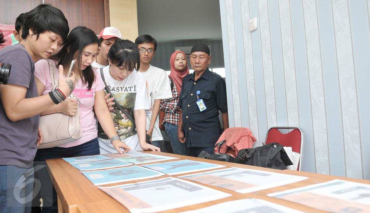Keluarga korban melihat foto properti dari jenazah korban KM Zahro yang belum teridenfikasi di RS Polri, Jakarta, Selasa (3/1). Penempelan foto hasil postmortem bertujuan untuk membantu pengenalan oleh pihak keluarga. (Liputan6.com/Yoppy Renato)