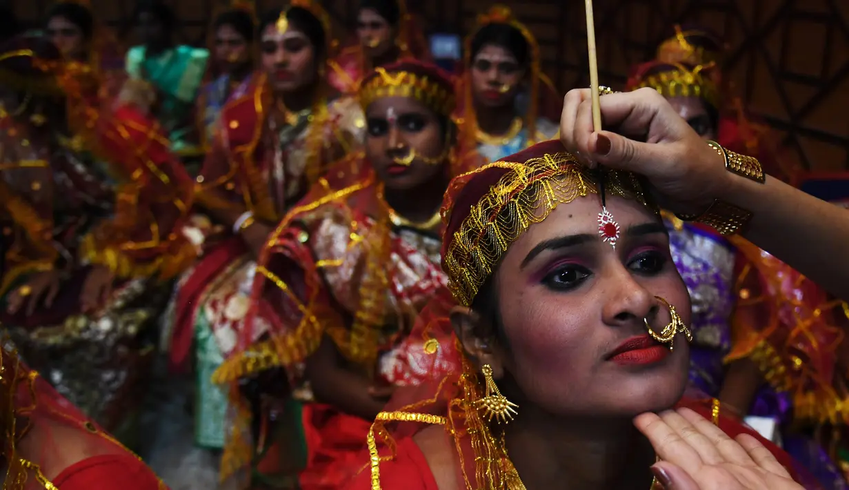 Seorang calon pengantin wanita dirias sebelum mengikuti upacara pernikahan massal di Kolkata, India (14/2). Acara nikah massal ini diselenggarakan oleh LSM setempat yang bertujuan untuk merayakan Hari Valentine. (AFP Photo/Dibyangshu Sarkar)