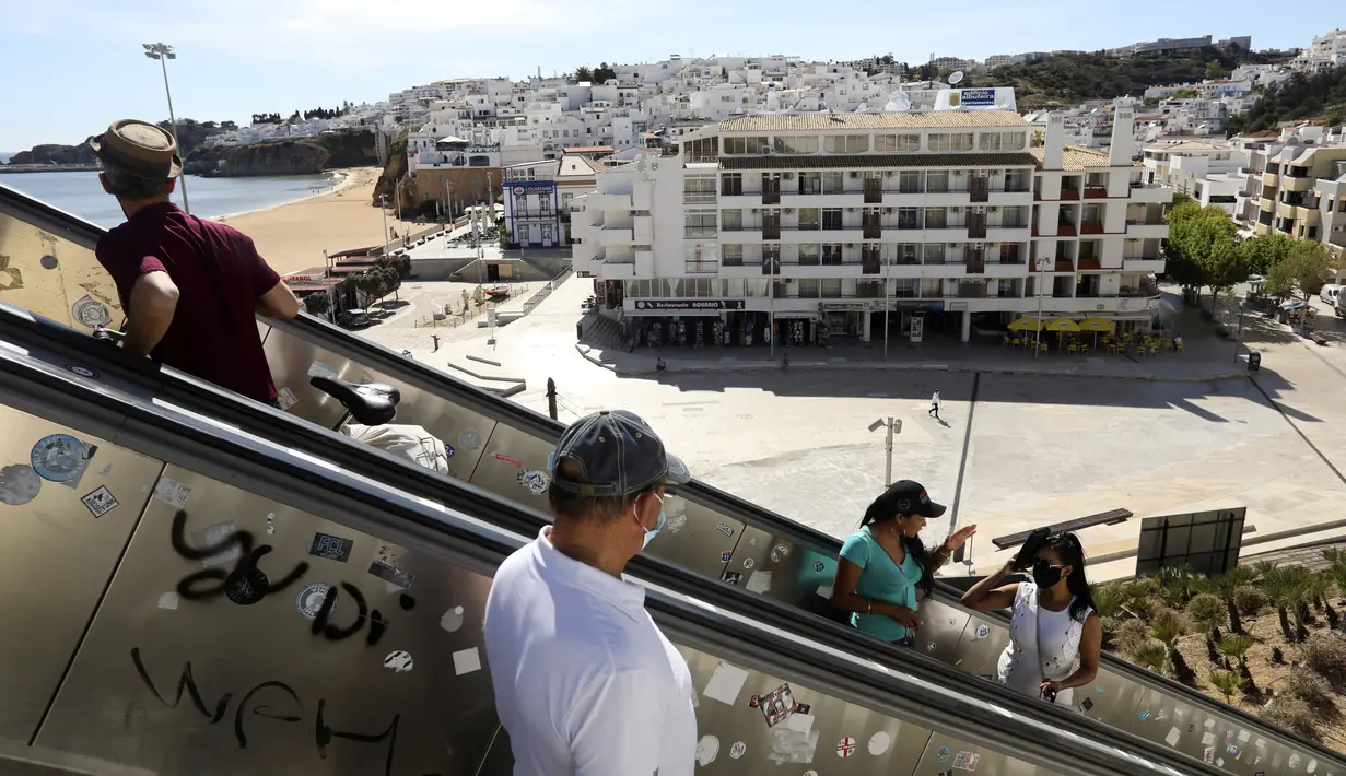 Orang-orang menggunakan eskalator di tepi pantai di Albufeira, wilayah Algarve, Portugal, Senin (17/5/2021). Wisatawan Inggris mulai berdatangan dalam jumlah besar di bagian selatan Portugal setelah pemerintah di kedua negara melonggarkan pembatasan perjalanan pandemi COVID-19 (AP Photo/Ana Brigida)