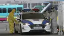 Petugas medis dengan pakaian pelindung mengambil sampel dari pengemudi di layanan "drive-thru" di Goyang, Korea Selatan, 1 Maret 2020. Drive thru (tanpa turun) virus Corona COVID-19 diberlakukan karena permintaan layanan tes kesehatan melonjak.  (AP/Ahn Young-joon)