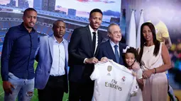 Bek Brasil Eder Militao (tengah) didampingi keluarganya berpose dengan Presiden Real Madrid Florentino Perez selama pengenal dirinya di stadion Santiago Bernabeu di Madrid, Spanyol (10/7/2019). (AP Photo/Manu Fernandez)