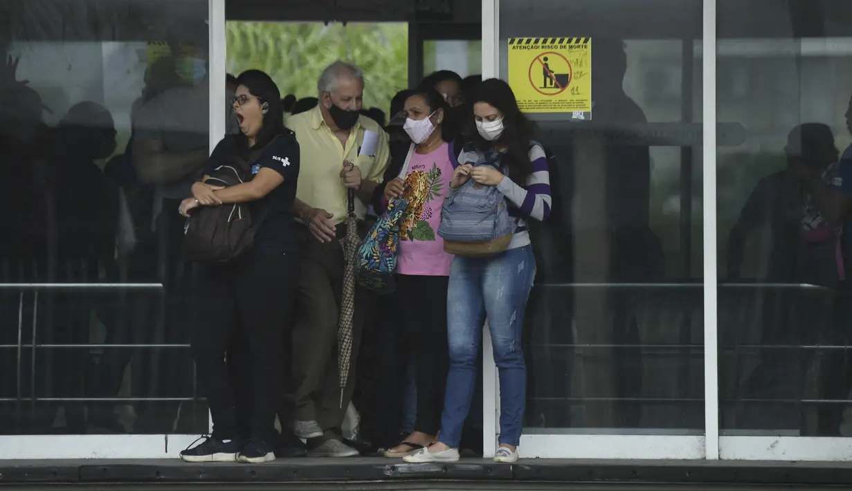Komuter menunggu bus BRT (Bus Rapid Transit) pada hari pertama pencabutan aturan wajib masker di luar ruangan, di Rio de Janeiro, Brasil, Kamis (28/12/2021). Pencabutan aturan wajib masker ini efektif berlaku pada Kamis (28/10) waktu setempat. (MAURO PIMENTEL / AFP)