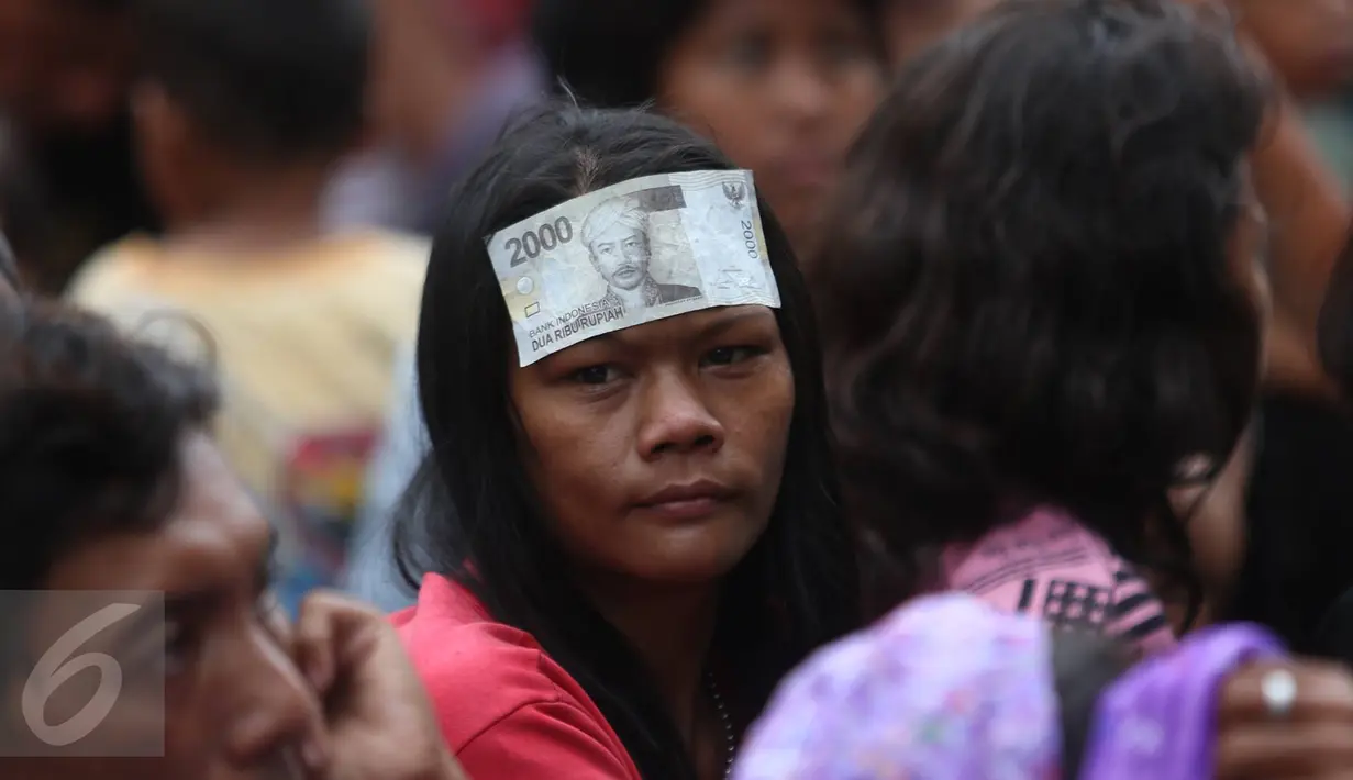 Seorang pengemis menempelkan angpao yang didapatkannya di selasar Vihara Dharma Bahkti, Petak Sembilan, Jakarta Barat, Sabtu (28/1). Mereka mengantre untuk mendapatkan uang angpau dari warga keturunan Tionghoa. (Liputan6.com/Imamnuel Antonius)