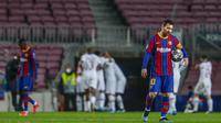 Striker Barcelona, Lionel Messi, tampak lesu usai ditaklukkan Paris Saint-Germain (PSG) pada laga Liga Champions di Stadion Camp Nou, Rabu (17/2/2021). Barcelona takluk dengan skor 1-4. (AP/Joan Monfort)