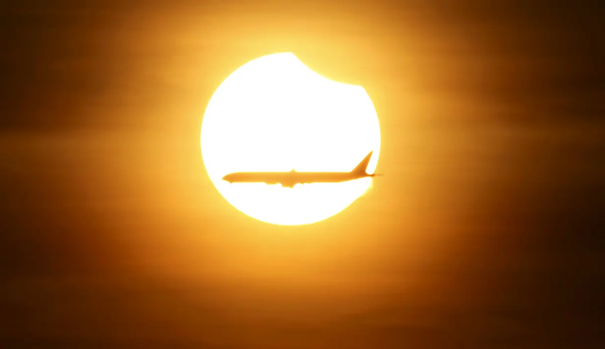 Sebuah pesawat terbang melewati gerhana matahari parsial yang terjadi di Singapura, Rabu (9/3/2016). Gerhana matahari parsial di Singapura terakhir kali terjadi pada 10 Mei 2013 lalu. (REUTERS / Edgar Su)
