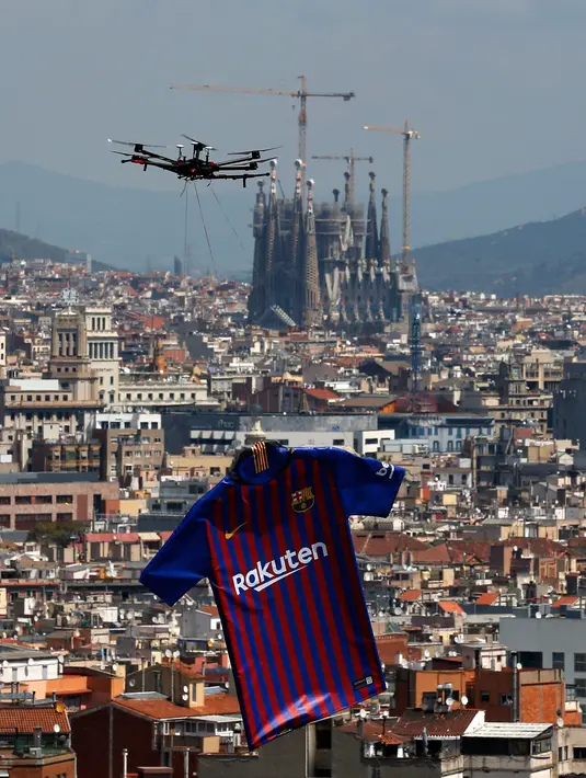 Sebuah drone menerbangkan jersey terbaru Barcelona untuk musim 2018/2019 saat diperkenalkan kepada publik di Montjuic Swimming Pool, 19 Mei 2018. Acara ini hanya berlangsung selama 15 menit yang dihadiri oleh seluruh skuad Barcelona. (AP/Manu Fernandez)