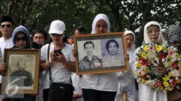 Warga Kompleks Zeni Mampang membawa foto keluarga mereka saat ziarah di TMP Kalibata, Jakarta, Minggu (1/11/2015). Mereka akan membongkar makam keluarga mereka di TMP jika pemerintah melakukan penggusuran terhadap rumah mereka. (Liputan6.com/Johan Tallo)