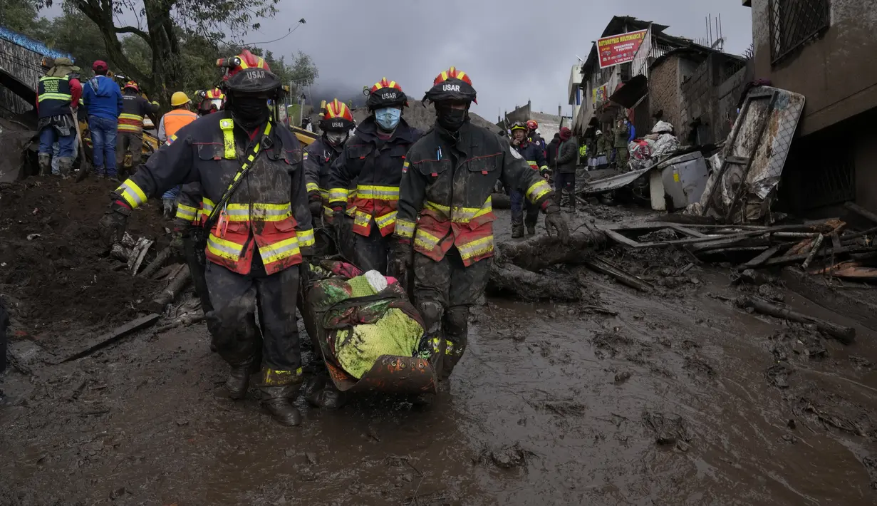 Petugas membawa jenazah korban banjir bandang yang dipicu oleh hujan yang memenuhi aliran sungai terdekat yang merusak mekanisme penahanan dan meruntuhkan lereng bukit dan membawa gelombang lumpur ke rumah-rumah di daerah La Gasca di Quito, Ekuador, Selasa (1/2/2022). (AP Photo/Dolores Ochoa)