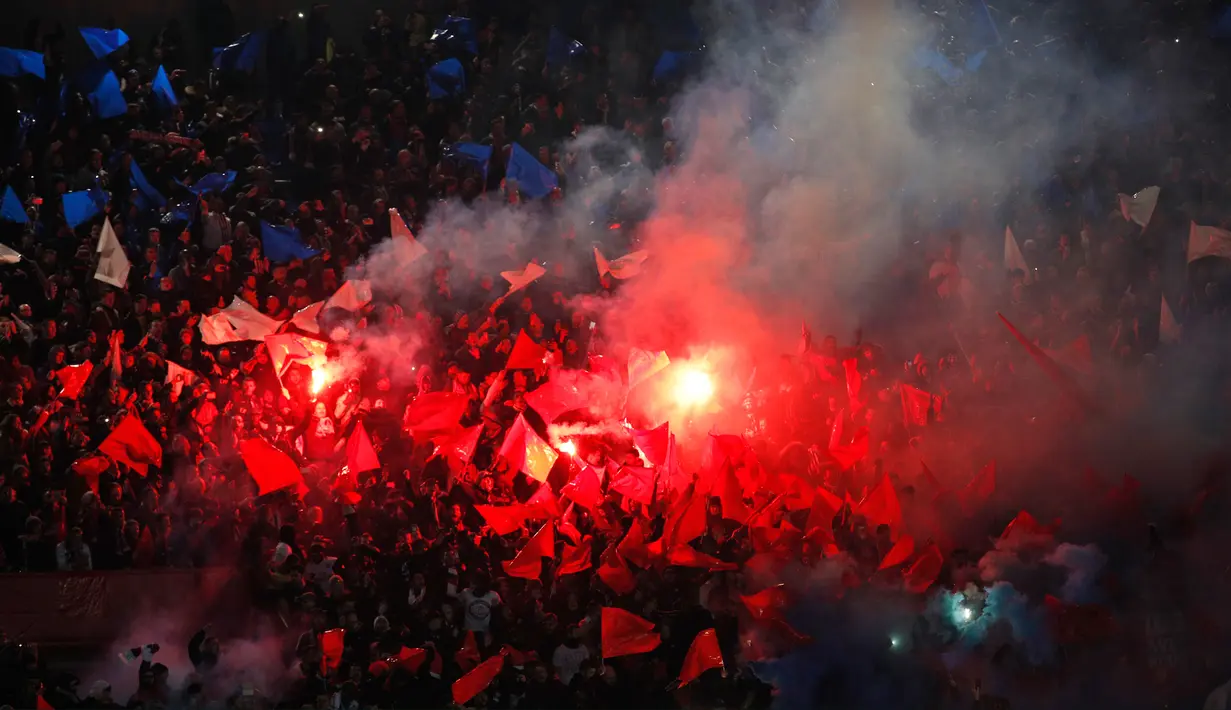 Para pendukung Paris Saint-Germain menyalakan suar sambil meneriakkan yel-yel dukungan saat pertandingan melawan Real Madrid di stadion Parc des Princes di Paris (6/3). (AP Photo / Francois Mori)