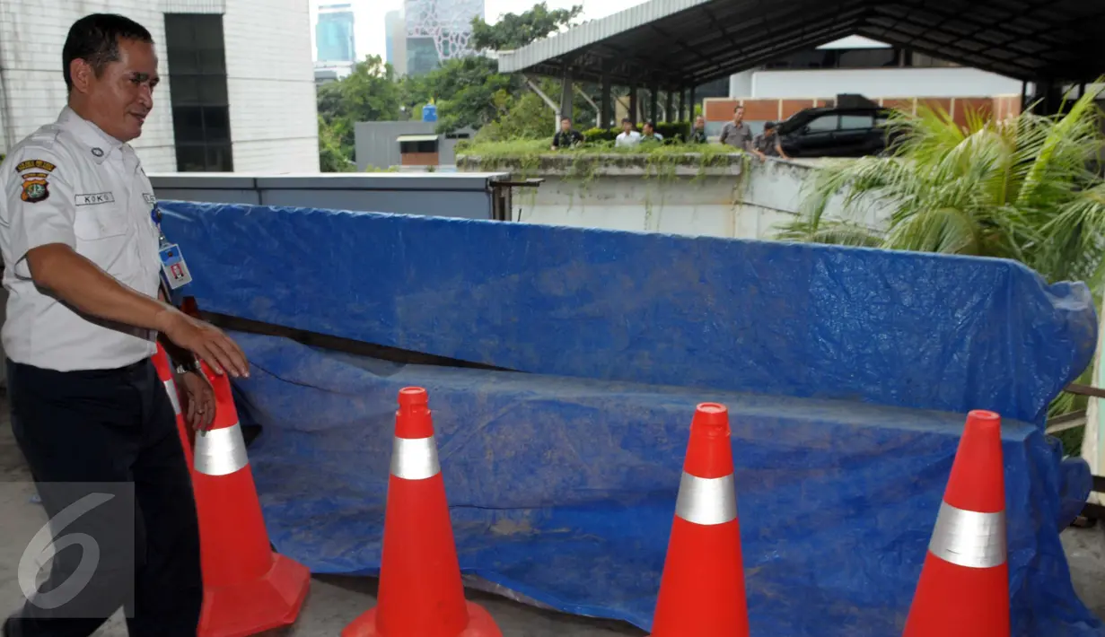 Petugas menutupi lokasi jatuhnya mobil Toyota Kijang warna merah marun dari lantai 3 Gedung Migas, Jakarta, Selasa (5/4). Mobil itu menabrak dinding pembatas di lantai 3 dan kemudian jatuh terbalik. (Liputan6.com/Helmi Affandi)