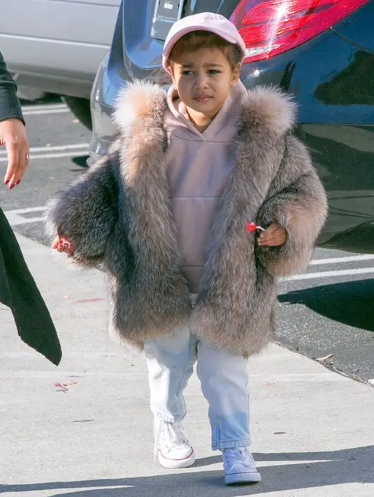 Di balik mantel bulu yang high-fashion itu, North West tampil sporty dengan sweater, wash denim dan sneakers dari Converse All Star seharga 27 poundsterling atau sekitar Rp 500 ribuan. (mirror.co.uk)
