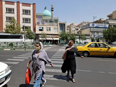 PeRempuan Iran menyeberang jalan di pusat kota Teheran ketika pihak berwenang memperketat pembatasan, Selasa (20/7/2021). Iran memberlakukan lockdown di Teheran dan provinsi terdekat setelah kasus infeksi Covid-19 mencapai rekor tertingginya selama wabah kelima. (ATTA KENARE/AFP)