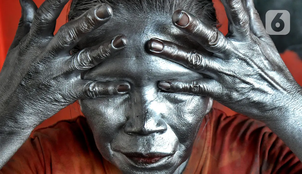 Pagi jelang siang pada  sudut toko perempatan lampu merah,  Nenek Mumum mulai merias wajah dan tubuhnya dengan cat silver. (merdeka.com/Arie Basuki)