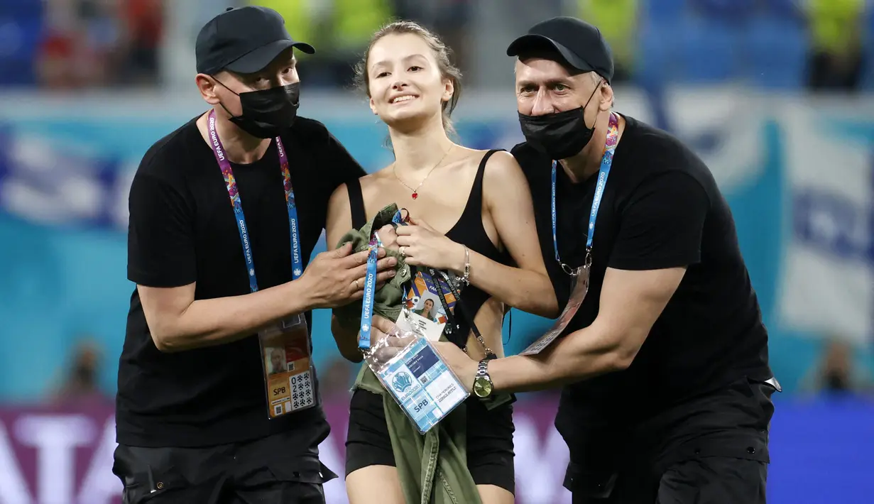 Petugas keamanan stadion menghentikan seorang penyusup lapangan wanita ketika pertandingan sepak bola Grup B UEFA EURO 2020 antara Finlandia melawan Belgia di Stadion Krestovsky, Saint Petersburg, Rusia, pada 21 Juni 2021. (AFP/Pool/Anatoly Maltsev)