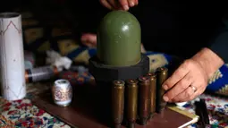 Seniman Suriah, Akram Abu Elfoz (37) ketika merangkai selongsong peluru dan sisa amunisi perang untuk dirangkai menjadi replika Masjid Al-Rawdah, di rumahnya di sebelah timur Ibu Kota Damaskus, 3 Juni 2016.  (AFP PHOTO/Sameer Al - Doumy) 
