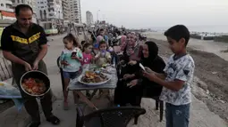 Anggota keluarga menyiapkan makanan mereka sambil menunggu berbuka puasa saat bulan suci Ramadan di pantai Kota Gaza, Palestina, Kamis (21/5/2020). Di tengah pandemi COVID-19, berbuka puasa bersama di pantai Kota Gaza tetap ramai. (AP Photo/Adel Hana)