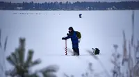 Seorang pria membuat lubang sebelum memulai memancing di tengah laut Bothnia yang sedang membeku di Vaasa, Finlandia, Rabu (27/12). Melalui lubang tersebut mereka memberikan umpannya kepada ikan buruan. (OLIVIER MORIN / AFP)