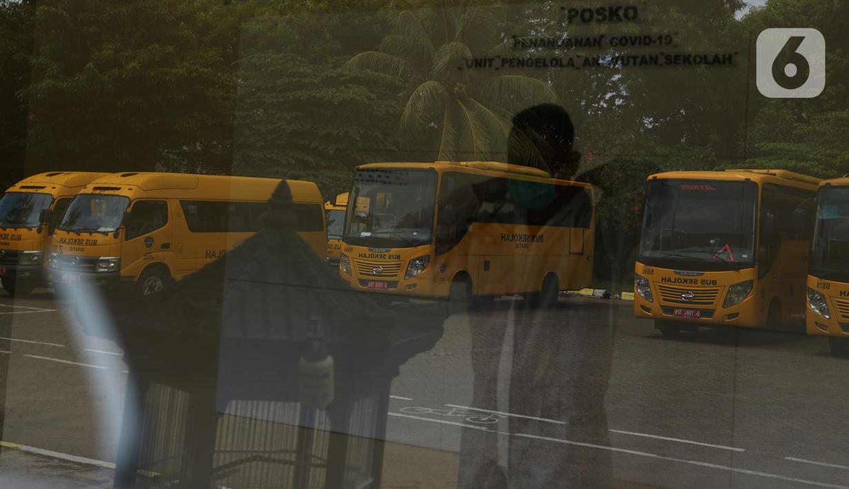 Petugas mengenakan APD sebelum menjemput pasien Covid-19 menggunakan bus sekolah di Puskesmas Jatinegara,  Jakarta, Selasa (22/9/2020). Sejumlah unit bus sekolah kini dialihfungsikan menjadi kendaraan untuk mengantar pasien Covid-19 berstatus OTG menuju Wisma Atlet. (merdeka.com/Imam Buhori)