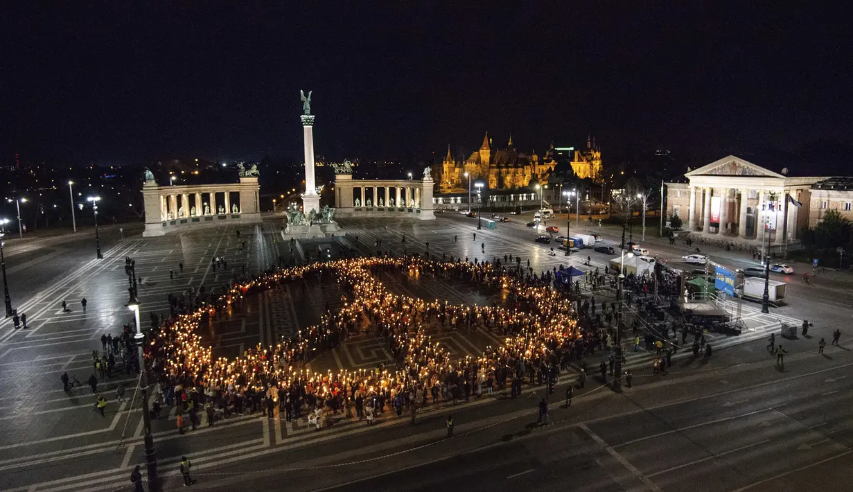 Orang-orang membuat tanda perdamaian dengan lampu saat demonstrasi untuk Ukraina yang diselenggarakan oleh Greenpeace di Heroes Square, Budapest, Hungaria, 9 Maret 2022. Lebih dari 1,5 juta orang telah menyeberang dari Ukraina ke negara-negara tetangga. (AP Photo/Anna Szilagyi)