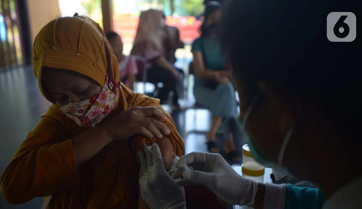 Petugas kesehatan menyuntikkan vaksin dosis ketiga (Booster) di RPTRA Kopi Gandaria, Pasar Rebo, Jakarta, Jumat (15/7/2022). Pemerintah Indonesia mewajibkan vaksinasi booster sebagai persyaratan untuk memasuki fasilitas publik/fasilitas umum antara lain perkantoran, tempat wisata, pusat perbelanjaan, dan area publik. (merdeka.com/Imam Buhori)