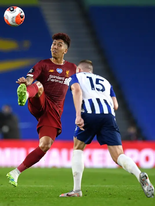 Penyerang Liverpool Roberto Firmino menendang bola melewati pemain Brighton & Hove Albion, Adam Webster pada lanjutan pertandingan Liga Inggris di Stadion Falmer, Kamis (9/7/2020) dini hari WIB. Liverpool berhasil kalahkan Brighton dengan skor 3-1. (AP Photo/Daniel Leal Olivas,Pool)