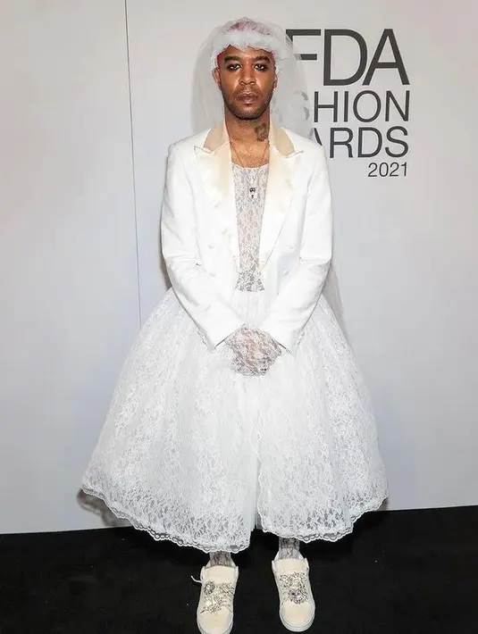 Kid Cudi tiba di penghargaan dengan gaun pengantin khusus oleh ERL. Rapper itu memadukannya dengan tuxedo jacket, sneakers berwarna krem, dan kerudung tulle. (Instagram/10menmagazine).