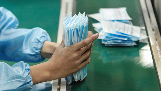 Pekerja memproduksi masker di sebuah pabrik di Yangzhou, Provinsi Jiangsu, China, Senin (27/1/2020). Masker tersebut diproduksi untuk mendukung pasokan bahan medis saat wabah virus corona melanda China. (STR/AFP)
