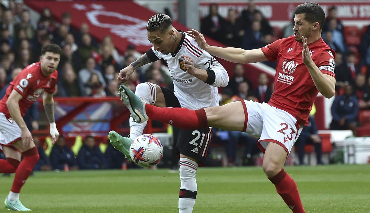 Pemain Manchester United, Antony (tengah) berebut bola dengan pemain Nottingham Forest, Remo Freuler saat laga pekan ke-31 Liga Inggris 2022/2023 di City Ground, Nottingham, Senin (17/04/2023) dini hari WIB. Setan Merah berhasil menang dengan skor 2-0. (AP Photo/Rui Vieira)