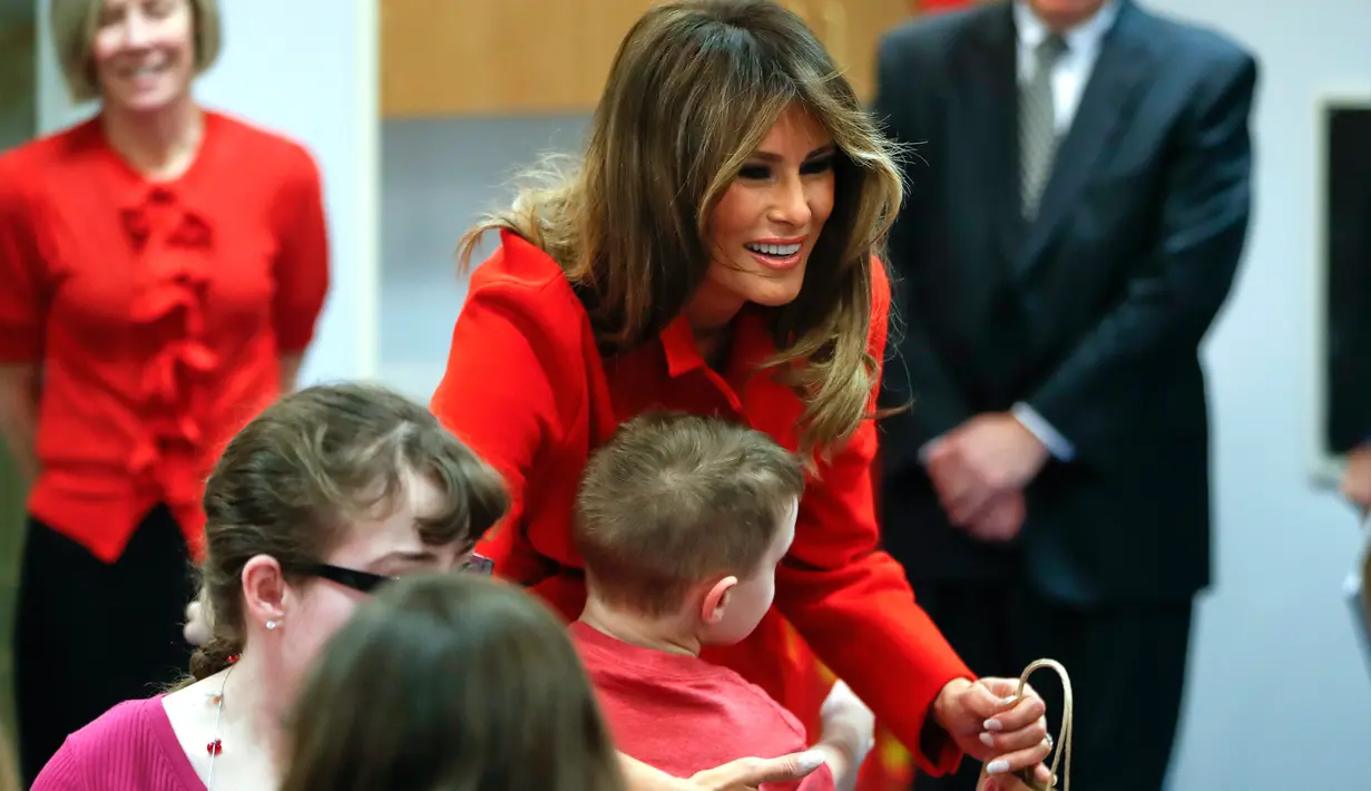 Istri Presiden AS Donald Trump, Melania Trump memeluk seorang anak saat berkunjung ke Children's Inn di National Institute of Health (14/2). (AP Photo/Pablo Martinez Monsivais)
