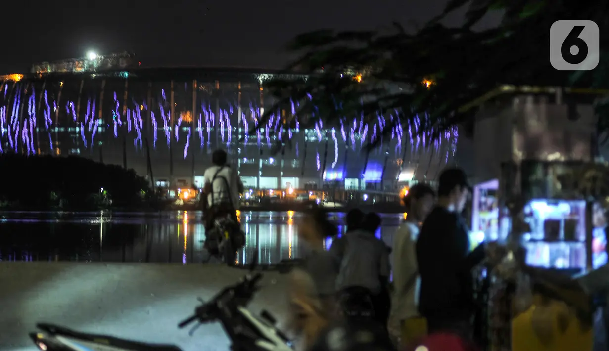 Warna-warni lampu Jakarta International Stadium (JIS) terlihat dari Waduk Cincin, Papanggo, Jakarta Utara, Rabu (16/3/2022). PT Jakarta Propertindo (Jakpro) menargetkan pembangunan JIS rampung dan siap dibuka pada April 2022. (merdeka.com/Iqbal S. Nugroho)