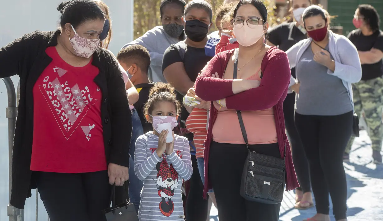 Sejumlah wanita dan anak-anak mengantre untuk menerima sumbangan pembalut wanita dan perlengkapan kebersihan lainnya di tengah pandemi COVID-19 di favela Paraisopolis, di Sao Paulo, Brasil (24/5/2021). Sumbangan ini disediakan oleh LSM lokal "G10 Favelas". (AP Photo/Andre Penner)