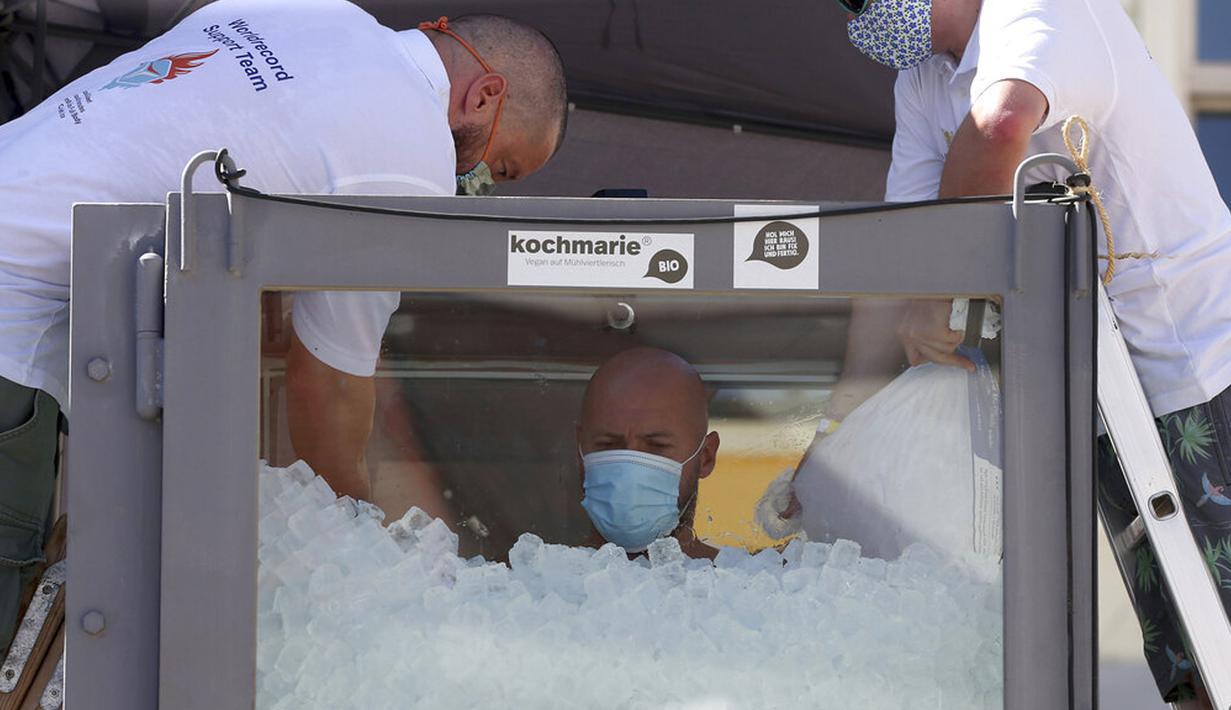 Perenang es Austria Josef Koeberl berdiri dalam kabin kaca berisi es di Melk, Austria, Sabtu (5/9/2020). Josef Koeberl berhasil memecahkan rekor dunia dengan berendam dalam es selama 2 jam, 30 menit, dan 57 detik. (AP Photo/Ronald Zak)