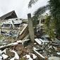 Pemandangan umum menunjukkan bangunan runtuh di Mamuju sehari setelah gempa bumi magnitudo 6,2 mengguncang Sulawesi Barat, Sabtu (16/1/2021). Petugas Badan Penanggulangan Bencana Daerah (BPBD) masih mendata jumlah kerusakan dan korban akibat gempa bumi tersebut. (Firdaus / AFP)