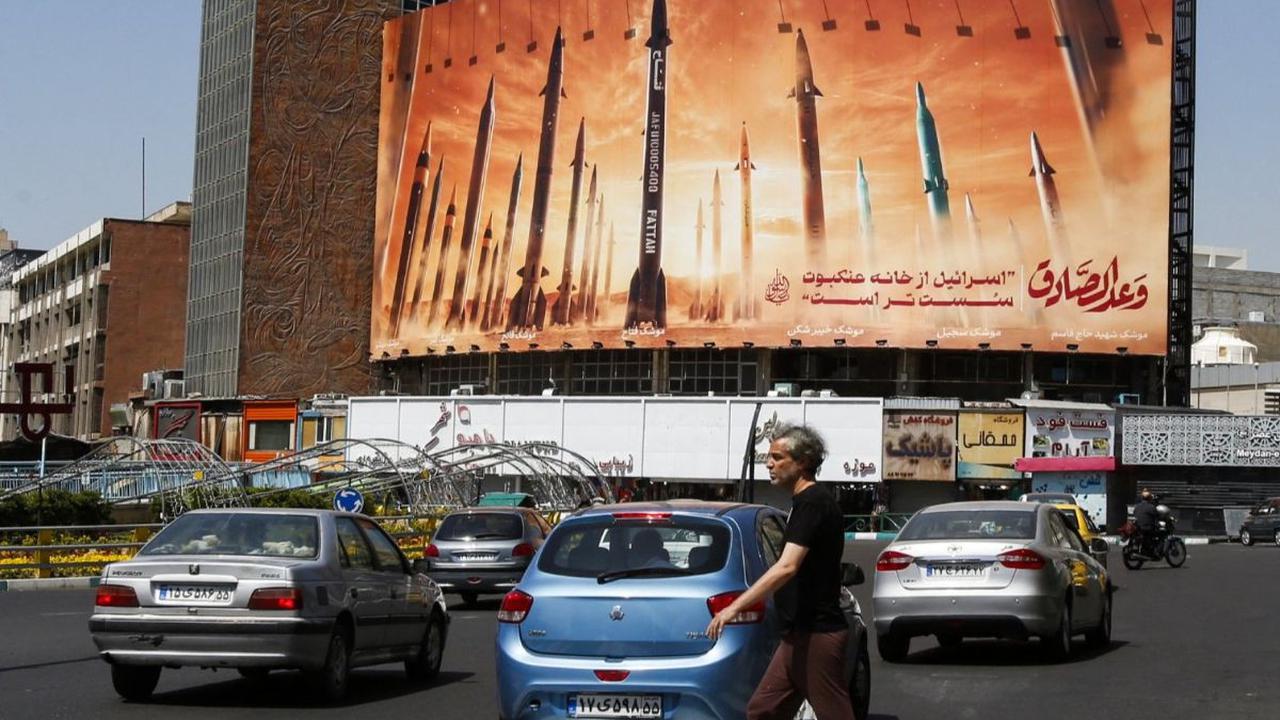 Seorang pria menyeberangi jalan di tengah lalu lintas yang ramai di Ibu Kota Teheran, Iran, Jumat (19/4/2024). Israel dilaporkan melancarkan serangan rudal terhadap fasilitas nuklir Iran di Isfahan sebagai balasan atas serangan pada akhir pekan lalu. AFP