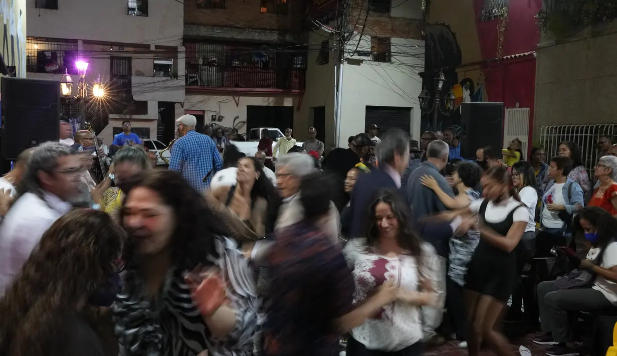 Orang-orang menari selama peresmian festival film pertama yang menampilkan film-film Venezuela di lingkungan San Agustín di Caracas, Venezuela (23/5/2022). Warga di San Agustin telah mengadakan acara budaya seperti ini selama bertahun-tahun, untuk mengubah budaya mereka yang dulu. (AP Photo/Ariana Cubillos)