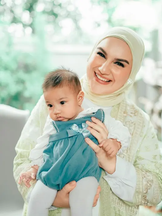 Potret keibuan yang cantik dari Irish Bella lainnya. Di sini, Irish mengenakan outfit bernuansa kuning, serasi dengan hijab yang dikenakannya, sedangkan sang buah hati mengenakan dress putih-hijau dengan detail pita yang menggemaskan. Foto: Instagram.