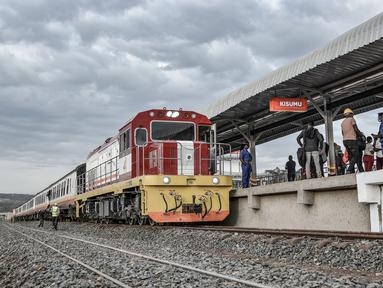 Sebuah kereta tiba di rel tempat penumpang menunggu untuk naik, di stasiun kereta Kisumu, Jumat (17/12/2021). Kereta api Kenya melanjutkan layanan komuter antara Nairobi dan Kisumu setelah tidak beroperasi selama lebih dari 10 tahun. (Brian ONGORO/AFP)