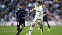 Gelandang Real Madrid, Luka Modric, berusaha melewati gelandang Real Valladolid, Leo Suarez, pada laga La Liga Spanyol di Stadion Santiago Bernabeu, Madrid, Sabtu (3/11). Madrid menang 2-0 atas Valladolid. (AFP/Javier Soriano)
