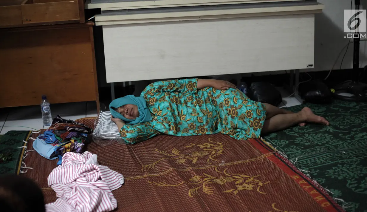 Seorang pengungsi wanita yang rumahnya terendam banjir tertidur saat mengungsi di Kelurahan Kampung Melayu, Jatinegara, Jakarta Timur, Rabu (7/2). Warga tidur hanya beralaskan tikar dan berselimut kain tipis. (Liputan6.com/Arya Manggala)