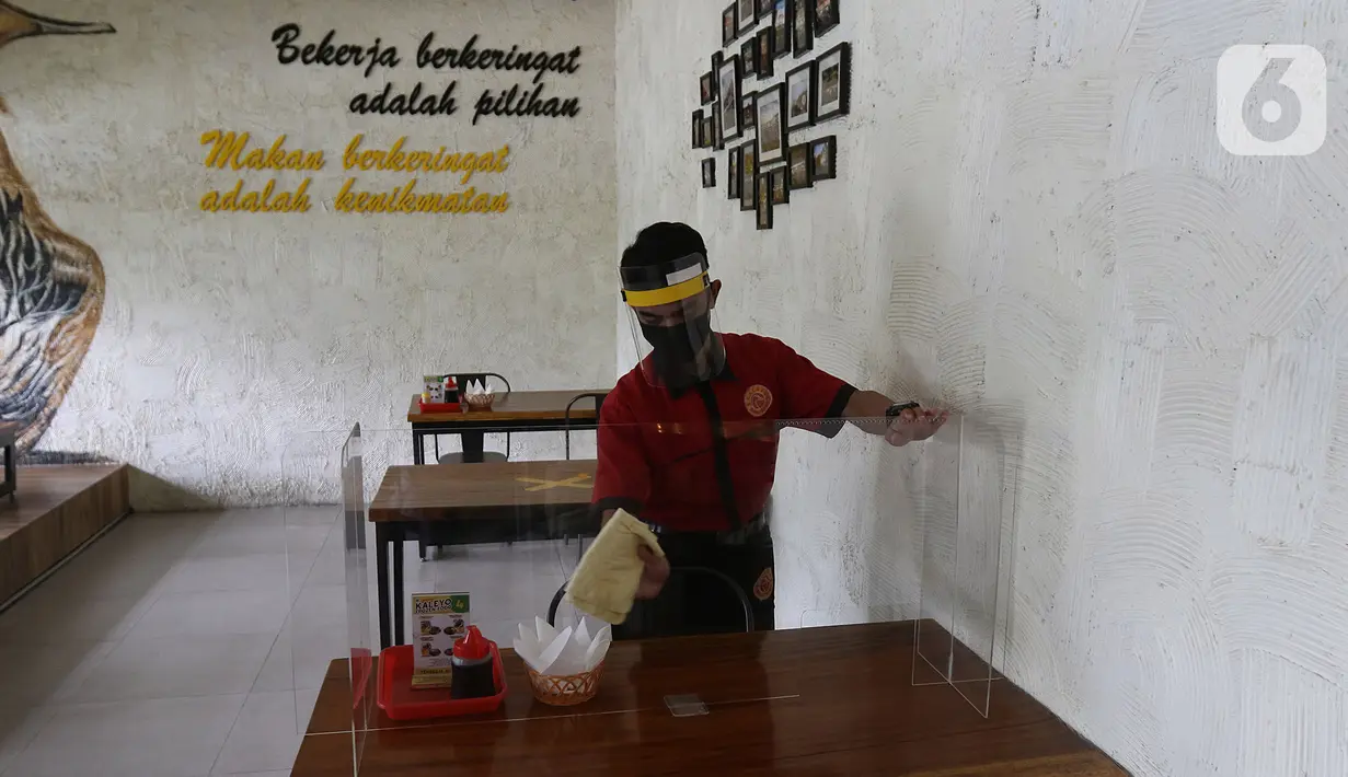 Pramusaji membersihkan meja di restoran Bebek Kaleyo, Kemanggisan, Jakarta, Senin (12/10/2020). Pada penerapan kembali masa PSBB Transisi Jakarta, restoran dan cafe diperbolehkan melakukan pelayanan makan di tempat dengan protokol kesehatan yang ketat. (Liputan6.com/Herman Zakharia)