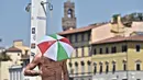 Seorang pria mengenakan topi payung saat mandi di Florence, Italia pada 1 Agustus 2017. Menurut laporan cuaca, Suhu diperkirakan mencapai 35-40 derajat celsius (95-104 Fahrenheit ) Di Italia tengah dan selatan,. (Maurizio Degl'Innocenti / ANSA via AP)