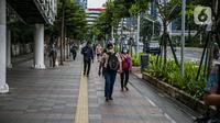 Pekerja kantoran berjalan di trotoar Jalan Sudirman, Jakarta Pusat, Rabu (6/1/2021). Selama pembatasan sosial berskala besar (PSBB) di wilayah Jawa dan Bali pada 11-25 Januari 2021, aktivitas bekerja di kantor diperketat dengan sistem work from home (WFH) 75 persen. (Liputan6.com/Faizal Fanani)